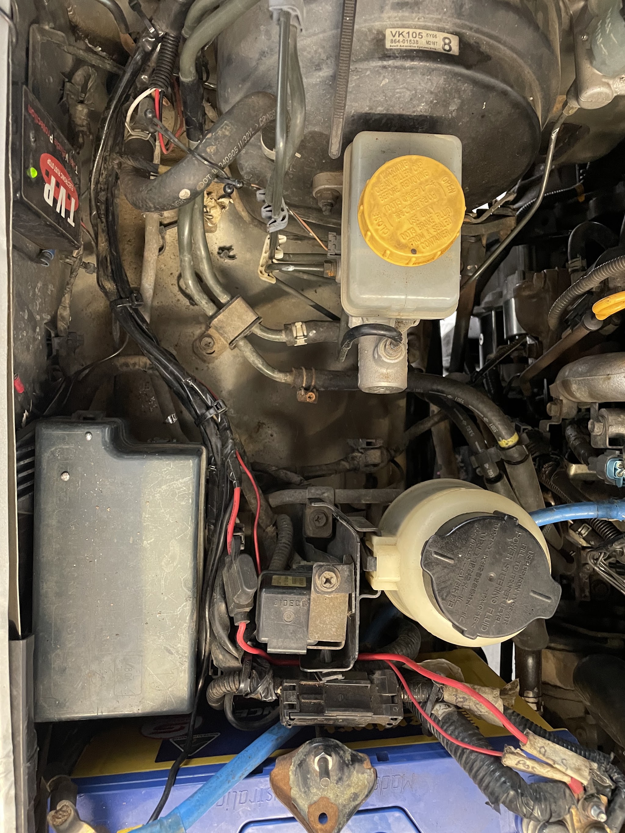 Engine bay wiring work in progress, with a rust protection module and battery fitted